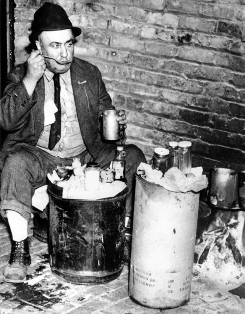 Albert Wendt, a cigar maker before the loss of his job, sits outdoors while cooking food in the city of Chicago, Ill., on June 22, 1938 during the Great Depression. (Photo by AP Photo)