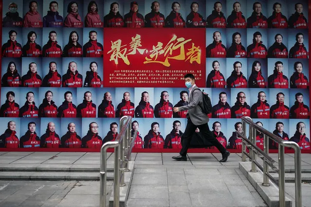 A pedestrian wears a protective mask while walking past a post showing portraits of medical workers who have been fighting COVID-19 in Wuhan on April 21, 2020 in Shanghai, China. Health authorities of China said the country has passed the peak of the COVID-19 epidemic on March 12. As of today, the Coronavirus (COVID-19) pandemic has spread to many countries across the world, claiming over 171,000 lives and infecting over 2.4 million people. (Photo by Yves Dean/Getty Images)