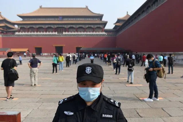 A security guard stands watch as people line up in queues managed to ensure social distancing, to enter the Forbidden City, the former palace of China's emperors, in Beijing on May 1, 2020. China's Forbidden City reopened on May 1, three months after it closed due to the coronavirus crisis – the latest signal that the country has brought the disease under control. (Photo by Greg Baker/AFP Photo)