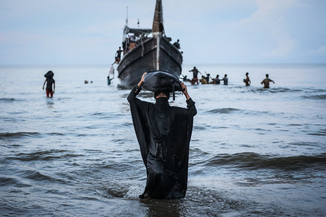 A Newly arrived Rohingya refugee walks to the beach after the local community decided to temporarily allow them to land for water and food in Ulee Madon, Aceh province, Indonesia, on November 16, 2023.return to a boat. About 250 Rohingya refugees reached western Indonesia on a overcrowded wooden boat on November 16, 2023, bringing the total number of refugees reported by local officials to have arrived this week to nearly 600. (Photo by Amanda Jufrian/AFP Photo)