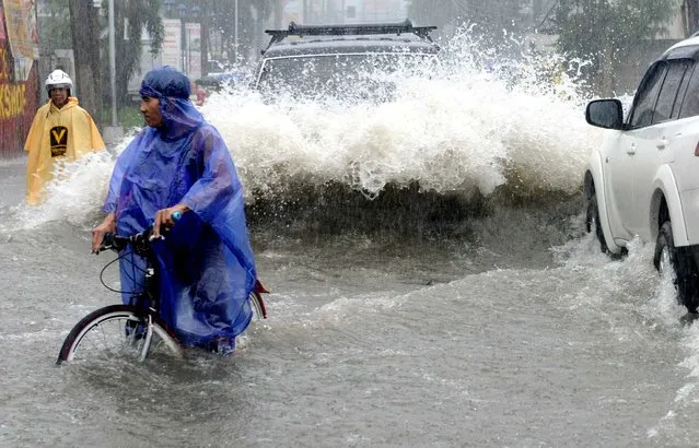 Commuters make their way through a flooded street in the suburbs of Manila on September 19, 2014. Heavy rains brought by the outer bands of Tropical Storm Fung-Wong shut down the Philippine capital on September 19, stranding motorists and forcing tens of thousands to flee their flooded homes, officials said. (Photo by Jay Directo/AFP Photo)
