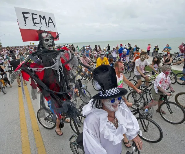 In this October 22, 2017 file photo provided by the Florida Keys News Bureau, Barry Gibson, left, costumed as the grim reaper, carries a Federal Emergency Management Agency sign while riding in the Fantasy Fest Zombie Bike Ride in Key West, Fla. The flamboyance of Fantasy Fest is a relief for business owners who say they’ve been trying to weather an economic storm that hit after Hurricane Irma battered the middle stretch of the tourism-dependent island chain last month. (Photo by Rob O'Neal/Florida Keys News Bureau via AP Photo)