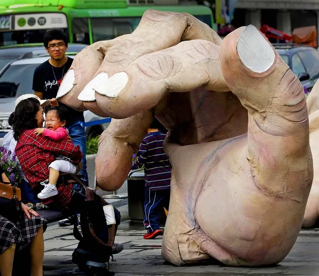 A girl cries as a massive hand approaches her during the Human Body Parts performance in the streets of Seoul, South Korea, on October 4, 2012. The performance is part of the Hi Seoul Festival which runs through October 7. (Photo by Lee Jin-man/Associated Press)