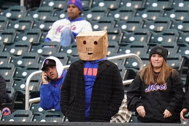 New York Mets fans, one wearing a paper bag over their head, watch as the Mets play the Washington Nationals during the first inning in the first baseball game of a doubleheader, Tuesday, October 4, 2022, in New York. (Photo by Frank Franklin II/AP Photo)