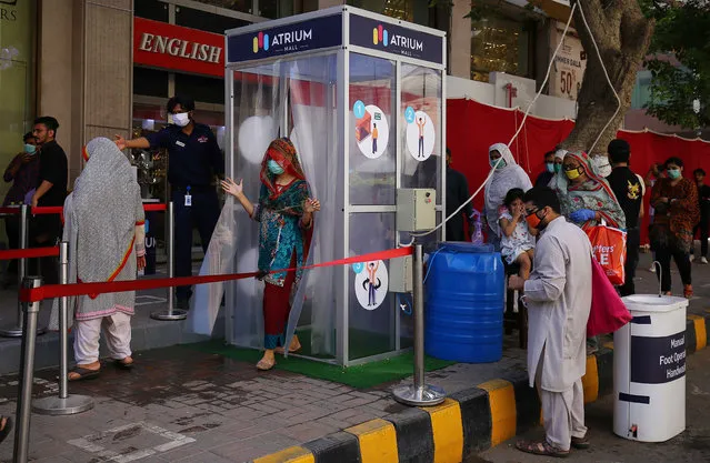 People walk through a disinfecting gate before entering a mall after government eases coronavirus restrictive measures in Karachi, Pakistan, 19 May 2020. Several countries around the world have started to ease COVID-19 lock-down restrictions in an effort to restart their economies and help people in their daily routines after the outbreak of coronavirus pandemic. (Photo by Shahzaib Akber/EPA/EFE)
