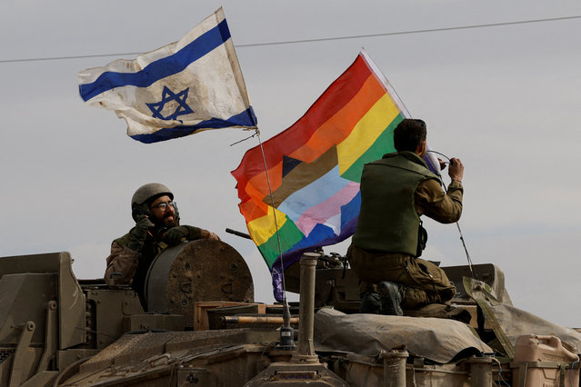 An Israeli soldier ties a rainbow flag with a Star of David on an Israeli armoured personnel carrier (APC), as they re-enter Israel from Gaza, amid the ongoing conflict between Israel and the Palestinian Islamist group Hamas, near the Israel-Gaza border, in southern Israel on January 11, 2024. (Photo by Tyrone Siu/Reuters)