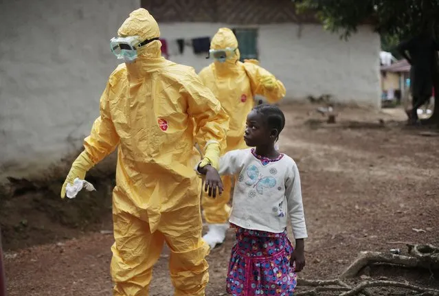 Nowa Paye, 9, is taken to an ambulance after showing signs of the Ebola infection in the village of Freeman Reserve, about 30 miles north of Monrovia, Liberia,Tuesday September 30, 2014. Three members of District 13 ambulance service traveled to the village to pickup six suspected Ebola sufferers that had been quarantined by villagers. (Photo by Jerome Delay/AP Photo)