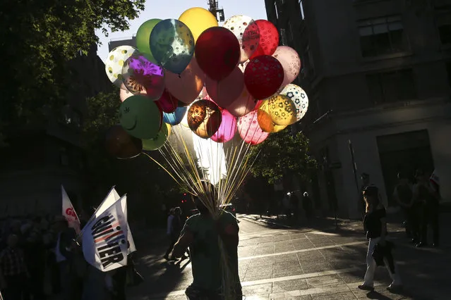 A balloon seller walks past people on their way to the closing rally for presidential candidate Alejandro Guillier, from the Nueva Mayoria coalition, in Santiago, Chile, Thursday, November 16, 2017. Chile will hold presidential and congressional elections on Sunday. (Photo by Esteban Felix/AP Photo)