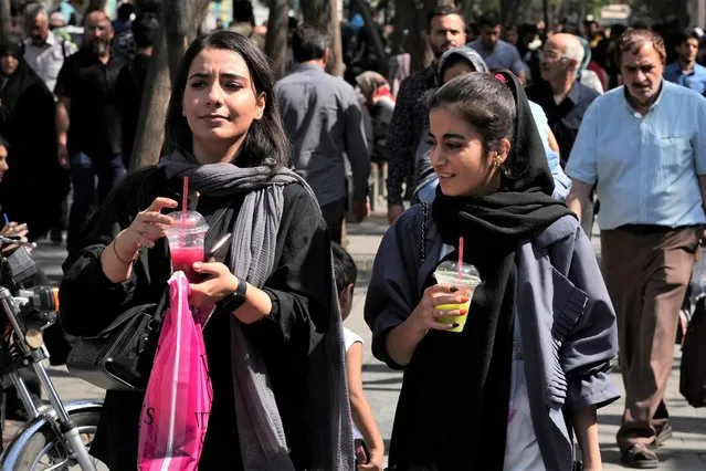 Two women drink a slushy while walking around in the old main bazaar of Tehran, Iran, Saturday, October 1, 2022. (Photo by Vahid Salemi/AP Photo)