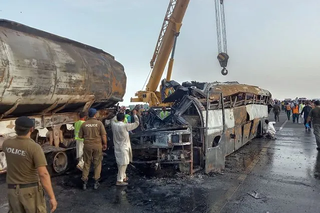 Police officers and workers remove the wreckage of a bus that collided with an oil tanker along a highway in Uch Sharif near Multan, Pakistan, Tuesday, August 16, 2022. A truck rammed into a minibus on a highway in eastern Pakistan overnight, causing a fire that killed and injured numerous passengers, a rescue official said Monday. (Photo by AP Photo)