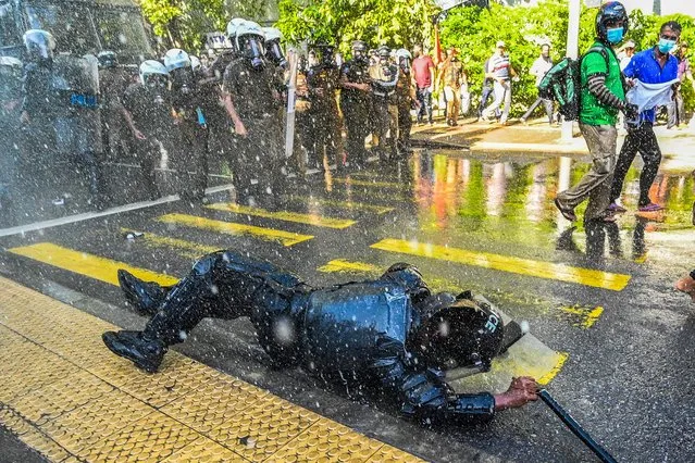 A security personnel falls as police use water cannons to disperse anti-government protestors during a demonstration in Colombo on September 24, 2022. Sri Lankan police dispersed hundreds of demonstrators on September 24, a day after severely curtailing protest rights in response to months of unrest sparked by the island nation's sharp economic downturn. (Photo by Ishara S. Kodikara/AFP Photo)