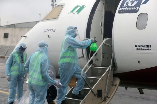 Cleaners wearing protective gear to protect against coronavirus sanitize the door of a plane upon its arrival from Abuja at the Murtala Mohammed Airport in Lagos Nigeria, Thursday July 9, 2020. Nigeria officials resumed domestic flights on Wednesday following months of closure to curb the spread of coronavirus in Africa's most populous country. (Photo by Sunday Alamba/AP Photo)
