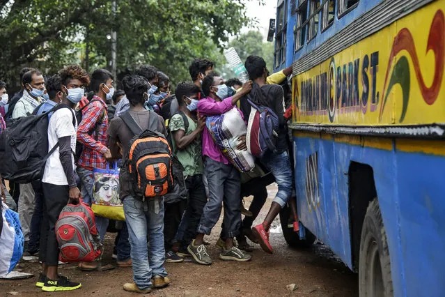 Commuters wearing face masks jostle for a ride on a bus discarding social distancing guidelines in Kolkata, India, Tuesday, July 21, 2020. With a surge in coronavirus cases in the past few weeks, state governments in India have been ordering focused lockdowns in high-risk areas to slow down the spread of infections. (Photo by Bikas Das/AP Photo)