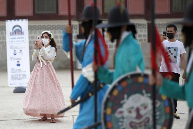 Visitors hold their smartphones while maintaining social distancing during a re-enactment ceremony of the changing of the Royal Guard at the Gyeongbok Palace, one of South Korea's well-known landmarks, in Seoul, South Korea, Friday, July 31, 2020. South Korea's newest coronavirus cases were mostly tied to international arrivals. (Photo by Lee Jin-man/AP Photo)