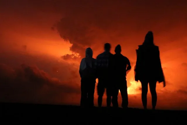 People watch the glow from lava erupting from Hawaii's Mauna Loa volcano, Monday, November 28, 2022 in Hilo, Hawaii. (Photo by Caleb Jones/AP Photo)