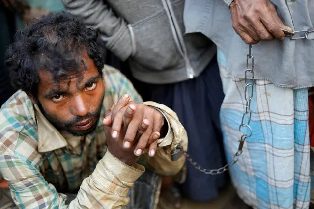 Asad Ali, a 60-year-old Rohingya refugee, keeps his 23-year-old mentally ill son Foyas Noor on a chain as they beg for food and money at a market at Kutupalong camp, near Cox's Bazar, Bangladesh January 15, 2018. (Photo by Tyrone Siu/Reuters)
