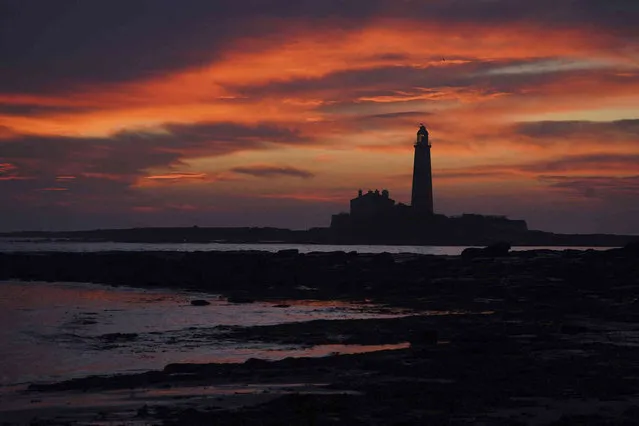 The sky turns orange above St Mary's Lighthouse in Whitley Bay on the North East coast of England just before sunrise, Friday October 21, 2022. (Photo by Owen Humphreys/PA Wire via AP Photo)