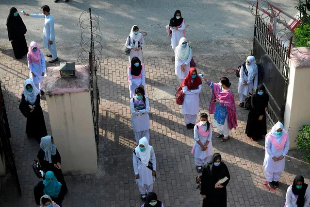 Teachers check the body temperature of students at the entrance of the Islamabad Model College of Commerce for Girls in Islamabad on September 15, 2020 after the educational institutes were reopened nearly six months after the spread of the Covid-19 coronavirus. (Photo by Aamir Qureshi/AFP Photo)