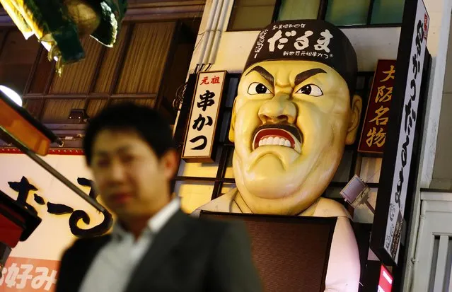 A man walks past an bas-relief advertising a Japanese restaurant in the Dotonbori amusement district of Osaka, western Japan November 19, 2014. (Photo by Thomas Peter/Reuters)