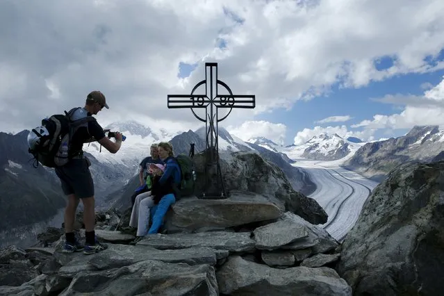 A man takes a picture of his family at the Eggishorn Summit with the Aletsch Glacier in the background in Fiesch, Switzerland, August 22, 2015. (Photo by Denis Balibouse/Reuters)