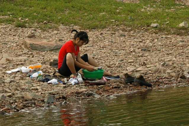 A woman washes shoes at the bank of the Yalu River, outside the North Korean town of Sinuiju, opposite Dandong in China's Liaoning province, September 11, 2016. (Photo by Thomas Peter/Reuters)