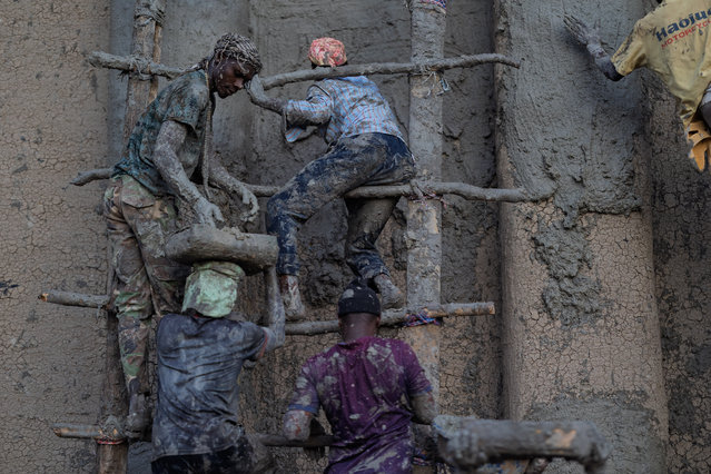 People scale handmade wooden ladders as they apply mud to re-plaster the Great Mosque of Djenne in Djenne, on June 12, 2025. Thousands of Malians converged before dawn on June 12, 2025 on the iconic mosque of Djenne, a World Heritage-listed historic town in central Mali, for the annual plastering of this earthen architectural gem. First built in the 13th century before being destroyed, the mosque was completely rebuilt in 1907 and is the largest earthen monument in the world, according to Unesco. (Photo by Ousmane Makaveli/AFP Photo)