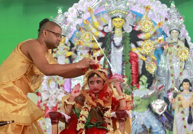 A Hindu priest adjusts the headgear of Nilanjana Chakraborty, a five-year old girl dressed as a Kumari, during the religious festival of Durga Puja in Agartala, India, October 21, 2015. Kumari is a young virgin girl who is worshipped as part of the Durga Puja rituals. The festival is the biggest religious event for Bengali Hindus. Hindus believe that the goddess Durga symbolises power and the triumph of good over evil. (Photo by Jayanta Dey/Reuters)