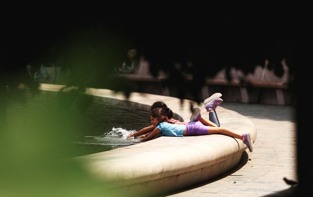 Children cool off at the Smithsonian Sculpture Garden’s fountain in Washington, DC. on August 7, 2025. (Photo by Kevin Lamarque/Reuters)