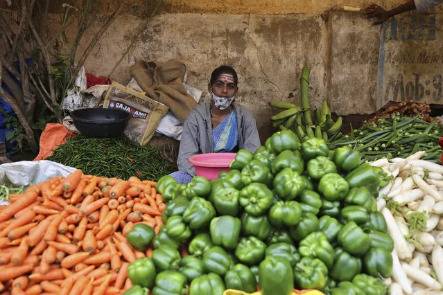A vegetable vendor wearing a face mask partly covering her face waits for customers in Bengaluru, India, Sunday, October 11, 2020. (Photo by Aijaz Rahi/AP Photo)