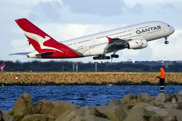 A Qantas A380 takes off from Sydney Airport over Botany Bay as a fisherman stands on breakwater in Sydney, Australia, Monday, September 5, 2022. Australian national carrier Qantas posted an underlying pre-tax half-year profit of 1.43 billion Australian dollars ($978 million) on Thursday, Feb. 23, 2023, in the airline's first return to profit since the coronavirus pandemic started three years ago. (Photo by Mark Baker/AP Photo)