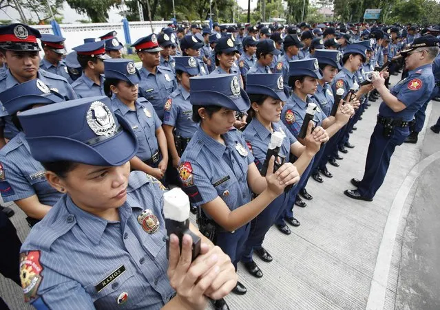 Female members of the Philippine National Police (PNP) hold their service pistols that are covered with tape during the sealing of the muzzles of firearms at the National Capital Region Police Office in Taguig, Metro Manila, December 22, 2014. A police officer said all policemen in the country are ordered to seal their firearms muzzles to prevent the indiscriminate firing of their weapons during Christmas and New Year holidays celebrations. (Photo by Erik De Castro/Reuters)