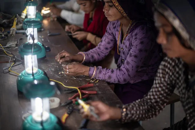 Indian villagers assemble solar lamps in a class held as part of the Barefoot Solar Project to bring solar powered lighting to rural areas on March 25, 2023 in Solawata, India. The college focuses on expanding access to electricity to help reduce poverty in rural and marginalised communities, training women to make and install solar lamps and lighting systems to bring clean solar energy to remote villages. (Photo by Rebecca Conway/Getty Images)