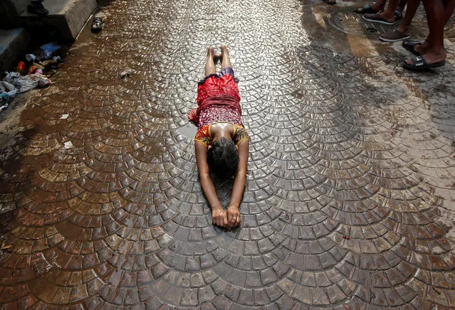 A girl lies on a road as she performs a ritual while worshipping Sheetala Mata, the Hindu goddess of smallpox, during Sheetala Puja in which devotees pray for betterment of their family and society, in Kolkata, India, April 14, 2018. (Photo by Rupak De Chowdhuri/Reuters)