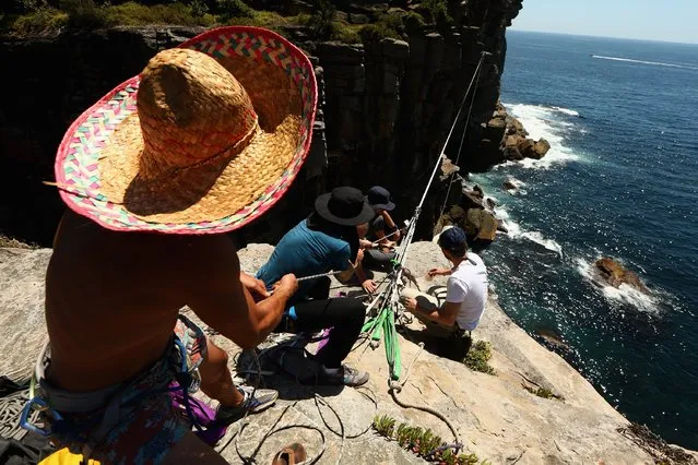 Slackliners adjust the tension of the webbing on their slackline rigged between two cliffs at Diamond Bay on December 21, 2014 in Sydney, Australia. (Photo by Cameron Spencer/Getty Images)
