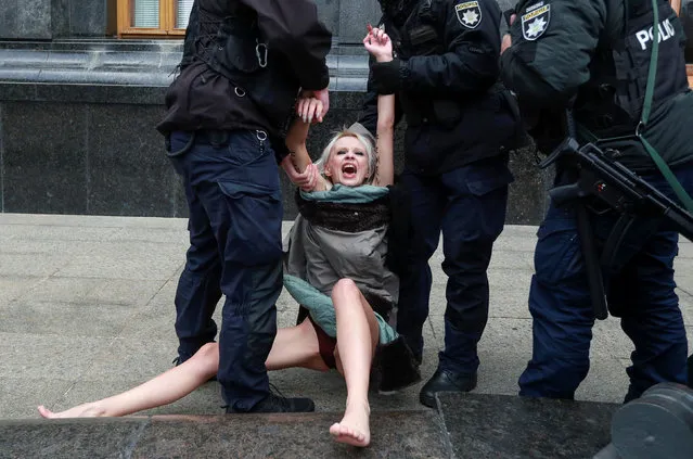 Ukrainian law enforcement officers restrain an activist of women's rights group Femen, who holds a protest outside the presidential administration headquarters while marking the International Day for the Elimination of Violence against Women in Kyiv, Ukraine on November 25, 2020. (Photo by Valentyn Ogirenko/Reuters)