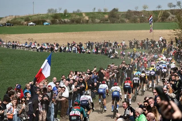 The pack of riders cycles over a cobblestone sector near Troisvilles, northern France, during the 120th edition of the Paris-Roubaix one-day classic cycling race, between Compiegne and Roubaix, northern France, on April 9, 2023. (Photo by Anne-Christine Poujoulat/AFP Photo)