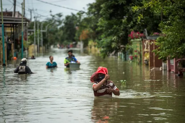 Residents evacuate their flooded homes in Gresik, East Java on December 15, 2020, as the rainy season brings floods to many areas in Jakarta and Java. (Photo by Juni Kriswanto/AFP Photo)