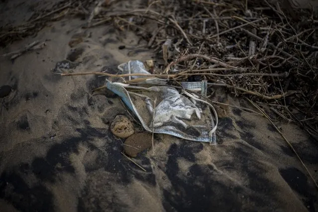A face mask, used as a preventive measure against the coronavirus, lies on the ground on a beach near Barbate, in Cadiz province, south of Spain, Saturday, February 5, 2022. Spain's government announced Tuesday it is scrapping a mandate to wear masks outdoors, as COVID-19 infection rates drop and hospitals report lower admissions. (Photo by Emilio Morenatti/AP Photo)