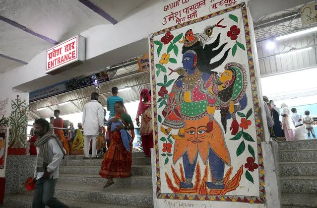 Passengers walk by the Madhubani artworks at the Madhubani railway station in Bihar, India, 07 April 2018 (issued 08 April 2018). Tourists and locals were flocking to the erstwhile forgotten Madhubani railway station in the eastern Indian state of Bihar, which has undergone a makeover after hundreds of local Mithila artists painted the station walls with the famous Madhubani artwork, known the world over for its unique geometrical patterns. 230 artists have painted over 2000 sq. meters of the station for free, although equipment was provided by the railway authorities, who claim these could be the largest Madhubani illustration in the world. Madhubani is one of the state of Bihar's oldest railway stations, and the makeover project comes as part of the Indian government's Swachh Bharat mission or Clean India Mission. The Mithila artwork, also known as Madhubani paintings, originated in Nepal and India, depicts scenes from folklore and mythology, including special designs for occasions such as birth and marriage. Artists used fingers, twigs, brushes, nib-pens, matchsticks and natural dyes and pigments to paint the Madhubani designs, a skill that is passed down through generations. Traditionally, Madhubani artwork – which boasts the coveted GI (Geographical Indication) tag – would adorn the walls and floors of huts in villages, although they are now painted mostly on cloth and canvas or handmade paper. The makeover has meant the number of daily visitors to the train station has more than doubled, according to a railway spokesperson. (Photo by Harish Tyagi/EPA/EFE)