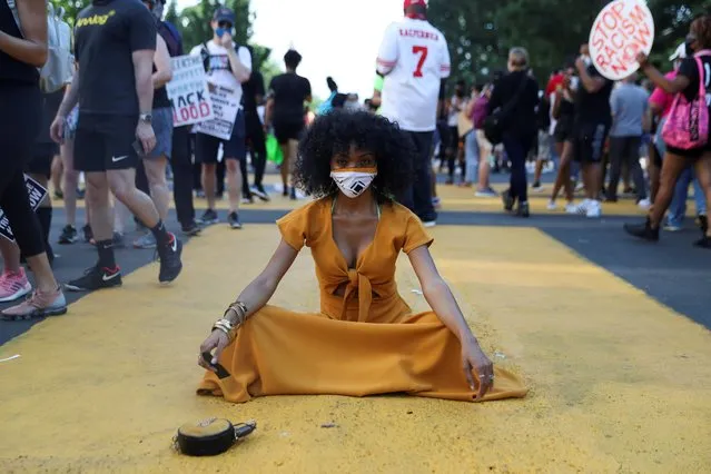 LaShawn Kenley sits in a part of a “Black Lives Matter” message painted on the street in front of the White House, as demonstrators take part in a protest against racial inequality in the aftermath of the death in Minneapolis police custody of George Floyd, in Washington, U.S., June 6, 2020. (Photo by Leah Millis/Reuters)
