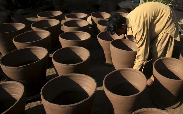 A worker moves drying clay bread ovens at a workshop outside Peshawar, Pakistan November 27, 2015. (Photo by Fayaz Aziz/Reuters)