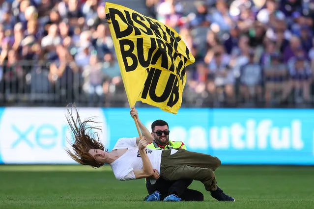 A pitch invader is tackled to the ground by a security guard during the round 10 AFL match between Walyalup/Fremantle Dockers and Geelong Cats at Optus Stadium, on May 20, 2023, in Perth, Australia. (Photo by Paul Kane/Getty Images)