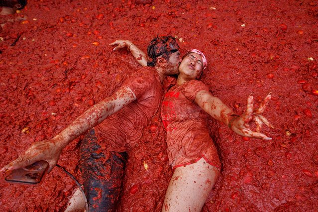 A couple kisses over a puddle of tomatoes during the annual “Tomatina” tomato fight fiesta, in the village of Bunol near Valencia, Spain, August 27, 2025. (Photo by Alberto Saiz/AP Photo)