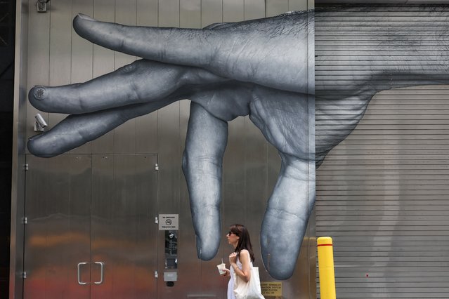 A woman walks past a mural in New York on June 23, 2025 after an excessive heat warning was issued for the New York City area. The United States is experiencing its first significant heat wave of the year, which began on June 20 across the Great Plains and expanding into parts of the Midwest and Great Lakes over the weekend, according to the National Weather Service (NWS). (Photo by Timothy A. Clary/AFP Photo)