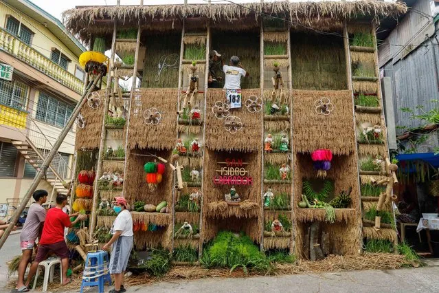 Residents decorate the exterior of their house with agricultural-themed designs on the eve of the Pahiyas Festival in Lucban municipality, Quezon Province, Philippines 14 May 2023. The Pahiyas Festival is celebrated annually in Quezon to honor San Isidro Labrador, the patron saint of farmers. Agriculture products are displayed on the facades of houses as a symbolic sign of gratitude for a good harvest. (Photo by Rolex dela Pena/EPA/EFE)