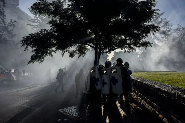 Health volunteers try to protect themselves from water during a clash with riot police during an anti-government demonstration on International Human Rights Day on December 10, 2020 in Santiago, Chile. After the massive protests that began in October 2019, Chile prepares to rewrite its dicatatorship-era constitution. During the social unrest, that lasted until March 2020, several police abuses were denounced by international organizations. Today is also the 14th anniversary of the death of Chilean dictator Augusto Pinochet who ruled the country between 1973 and 1990. (Photo by Claudio Santana/Getty Images)