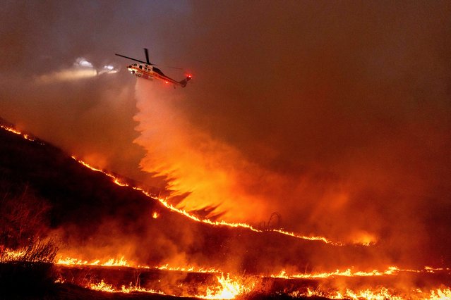 Water is dropped by helicopter on the Kenneth Fire in the West Hills section of Los Angeles, Thursday, January 9, 2025. (Photo by Ethan Swope/AP Photo)
