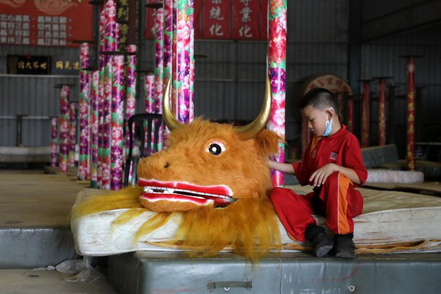 A member of the Kun Seng Keng Lion and Dragon Dance Association, touches an ox mask designed for Lunar New Year at a training centre, in Muar, Malaysia on February 5, 2021. (Photo by Lim Huey Teng/Reuters)
