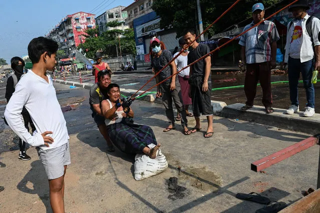 Protesters test out a large slingshot weapon in Yangon on March 17, 2021, as security forces continued a crackdown on demonstrations against the military coup. (Photo by AFP Photo/Stringer)