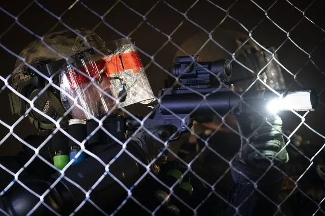 A police officer prepares to fire a less-lethal round at demonstrators during a protest over Sunday's fatal shooting of Daunte Wright during a traffic stop, outside the Brooklyn Center Police Department, Wednesday, April 14, 2021, in Brooklyn Center, Minn. (Photo by John Minchillo/AP Photo)